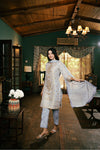 Woman in a patterned kurta and pants standing in a room with wooden ceiling and decor.