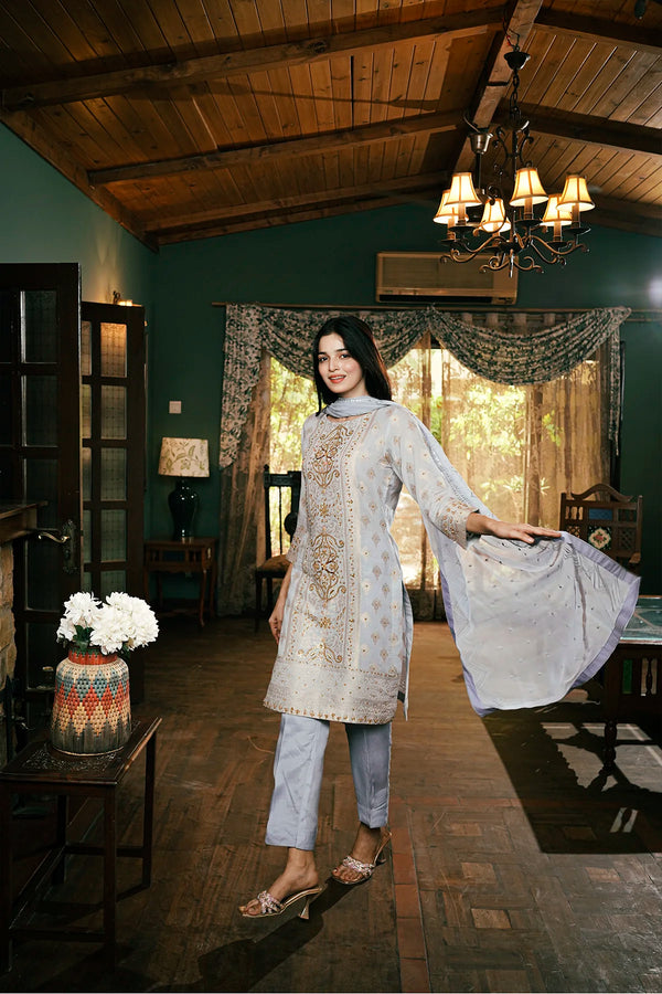 Woman in a patterned kurta and pants standing in a room with wooden ceiling and decor.