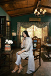 Woman sitting in a decorated room with wooden furniture and decorative elements.
