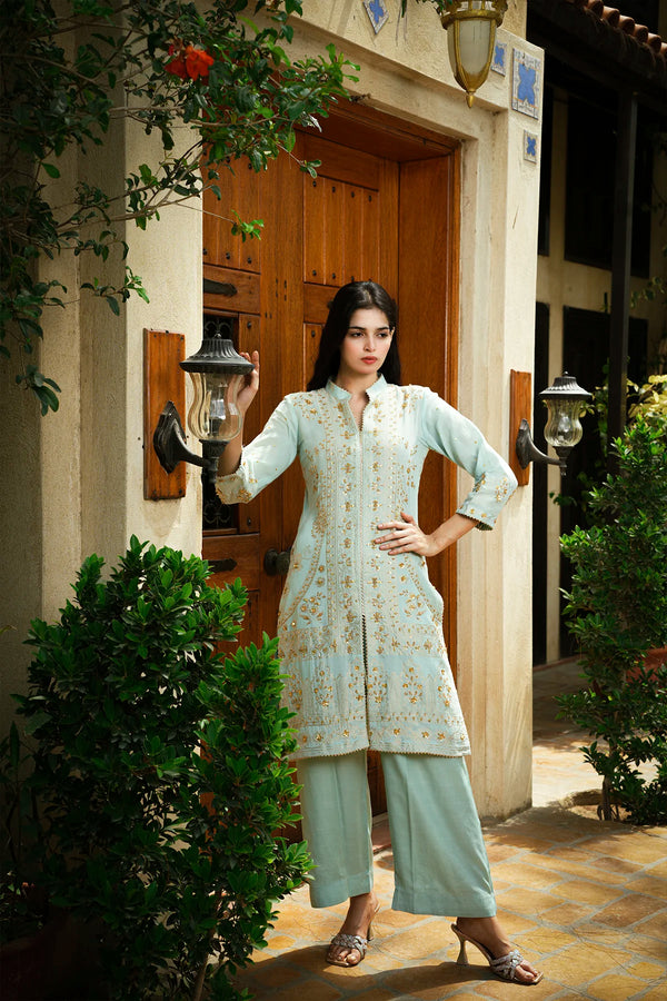 Woman in a traditional outfit standing in front of a building entrance.
